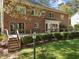 Back of brick home with wooden deck overlooking a green lawn and landscaping at 4533 Wood Valley Dr, Raleigh, NC 27613