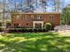 Expansive brick home with a large lawn, deck, and manicured hedges in the backyard at 4533 Wood Valley Dr, Raleigh, NC 27613
