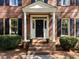 Inviting front entrance with brick steps, white columns, and a classic black front door at 4533 Wood Valley Dr, Raleigh, NC 27613