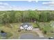 Expansive aerial view of a white farmhouse-style home surrounded by lush greenery and a private pond at 6024 Lunenburg Dr, Raleigh, NC 27603