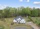 Overhead view of a white farmhouse style home with lush green landscaping, trees, and surrounding pond at 6024 Lunenburg Dr, Raleigh, NC 27603