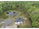 Wide aerial shot of a house with a pond, forest, and a well-manicured backyard with a patio at 6024 Lunenburg Dr, Raleigh, NC 27603