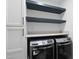 Modern laundry room featuring front loading washer/dryer and functional shelving above at 6024 Lunenburg Dr, Raleigh, NC 27603