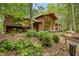 A beautiful brown home featuring a wall of windows, a wooden deck, and lush green landscaping at 673 Brookview Dr, Chapel Hill, NC 27514