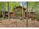 A beautiful brown home featuring a wall of windows, a wooden deck, and lush green landscaping at 673 Brookview Dr, Chapel Hill, NC 27514