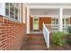 Charming brick home featuring a covered front porch and a white spindle railing and columns at 6804 Justice Dr, Raleigh, NC 27615