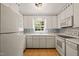 A bright kitchen featuring all-white appliances and cabinetry paired with stylish blue striped wallpaper accents at 6804 Justice Dr, Raleigh, NC 27615