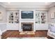Cozy living room featuring a fireplace with stone surround and built-in bookshelves and cabinets at 7101 Gibson Creek Pl, Cary, NC 27519