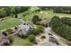 Aerial view of a stone clubhouse with a porte cochere, surrounded by a golf course and lush greenery at 8208 Bella Oak Ct, Wake Forest, NC 27587