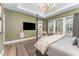 Well-lit bedroom with elegant decor, a tray ceiling with chandelier, and backyard views at 8208 Bella Oak Ct, Wake Forest, NC 27587