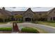Exterior of the clubhouse showcases stone architecture, arched entryway, and landscaped circular drive at 8208 Bella Oak Ct, Wake Forest, NC 27587