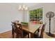 Dining room with a wooden table, chairs, modern chandelier, and bright window showcasing lush greenery at 918 Albany Ct, Raleigh, NC 27615