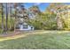 View of light blue home with a large lawn, surrounded by lush trees and a blue sky backdrop at 924 Lynn Rd, Durham, NC 27703