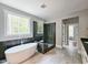 Modern bathroom with standalone tub, glass shower enclosure, and tiled floor and walls plus a view to outside at 97 Fox Oak Trl, Pittsboro, NC 27312