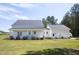 Exterior of house with covered porch, bushes, manicured lawn, and overcast sky at 9947 Nc Hwy 96 N, Selma, NC 27576
