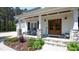 Charming front porch with stone pillars and rocking chairs, leading to a wooden double door entrance at 9947 Nc Hwy 96 N, Selma, NC 27576