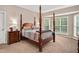 A bedroom with a beautiful wooden four-poster bed and bright windows with natural light and neutral walls at 1027 Upchurch Farm Ln, Cary, NC 27519