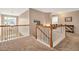 Landing area with stairs, carpet, white and wooden railing, and a modern light fixture at 1027 Upchurch Farm Ln, Cary, NC 27519