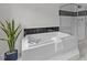 Close-up of a large bathtub with black tile accents and a glass-enclosed shower in an all-white bathroom at 103 Ticonderoga Rd, Cary, NC 27519