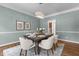 Charming dining room with a light blue wall, a modern chandelier, hardwood floors, and beautiful floral-themed artwork at 103 Ticonderoga Rd, Cary, NC 27519