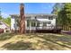 Rear exterior showcasing a white house with a brick chimney, deck, and expansive lawn at 103 Ticonderoga Rd, Cary, NC 27519