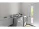 Well-lit laundry room featuring a washer, dryer, utility sink, and access door to the exterior at 103 Ticonderoga Rd, Cary, NC 27519