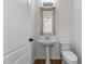 Stylish powder room featuring a pedestal sink, decorative mirror, and white toilet at 103 Ticonderoga Rd, Cary, NC 27519