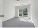 Sunlit bedroom featuring a large window that brightens the room with neutral walls and carpet at 107 Kinship Ln, Apex, NC 27502