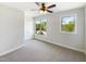 Bright, carpeted bedroom featuring a ceiling fan and two windows with neighborhood views at 108 Warm Wood Ln, Apex, NC 27539