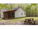 Home exterior showcasing a wooden picnic table and a screened-in porch set among trees at 1106 Lake Ridge Dr, Creedmoor, NC 27522
