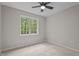 Bedroom featuring ceiling fan, neutral carpet and paint, and window with wooded view at 1106 Lake Ridge Dr, Creedmoor, NC 27522