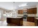 Well-lit kitchen with dark wood cabinets, granite counters, stainless steel appliances, and an island at 138 Horizon Trl, Garner, NC 27529
