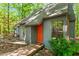 Charming home exterior featuring a modern gray facade, orange front door, and wooden walkway in a wooded setting at 158 Poplar St # A, Chapel Hill, NC 27516