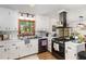 Bright kitchen featuring white cabinets, black appliances, and a window overlooking the yard at 1636 Cone Ave, Apex, NC 27502