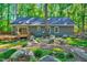 Tranquil backyard with a wooden deck, lush greenery, mature trees, and natural rock landscaping at 1715 Us 15-501 S, Chapel Hill, NC 27517