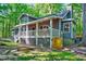 Charming gray home featuring a covered porch and lush green lawn with mature trees at 1715 Us 15-501 S, Chapel Hill, NC 27517