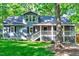 Charming gray home featuring a covered porch, black shutters, and a lush green lawn with mature trees at 1715 Us 15-501 S, Chapel Hill, NC 27517