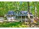 Gray home features a charming front porch and steps leading to a landscaped yard with mature trees at 1715 Us 15-501 S, Chapel Hill, NC 27517
