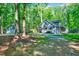 View of the charming gray home with a separate garage surrounded by lush, mature trees and a gravel driveway at 1715 Us 15-501 S, Chapel Hill, NC 27517