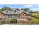 Backyard with patio, brick exterior, manicured lawn, and trees in the distance at 2066 Lake Point Dr, Graham, NC 27253