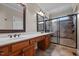 A bathroom featuring double sinks, brown cabinets, and a tile shower with glass doors at 2066 Lake Point Dr, Graham, NC 27253