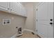 Bright laundry room with storage cabinets, tile floor, and white door at 2066 Lake Point Dr, Graham, NC 27253