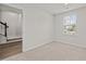 Cozy bedroom with a bright window, neutral carpet, light walls, and stairs nearby at 209 Timber Forest Ln, Cary, NC 27519