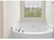 Close up of a luxurious soaking bathtub with chrome hardware near a window at 2103 Glenkirk Dr, Burlington, NC 27215