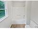 Compact bathroom with a tub/shower combo, light wood-look flooring, and a window for natural light at 213 Dwelling Pl, Knightdale, NC 27545