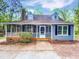 Charming blue home featuring a screened porch, dormer windows and lush green surroundings at 213 Dwelling Pl, Knightdale, NC 27545