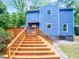 Two-story blue home with a wooden deck and stairs, surrounded by lush greenery at 213 Dwelling Pl, Knightdale, NC 27545