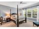 Light-filled bedroom featuring a four-poster bed, neutral walls, and bright windows overlooking greenery at 262 Windgate Dr, Clayton, NC 27527