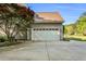 Attached two-car garage with a white door, complemented by nearby landscaping and mature trees at 262 Windgate Dr, Clayton, NC 27527