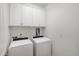 Well-lit laundry room features washer, dryer and wall-mounted storage cabinets at 317 Castle Rock Ln, Cary, NC 27519